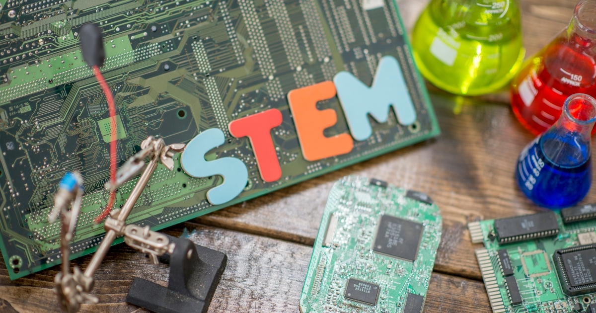 STEM-themed setup featuring colorful letters spelling 'STEM,' circuit boards, electronic components, and colorful science beakers, symbolizing hands-on learning and innovation in science, technology, engineering, and math.