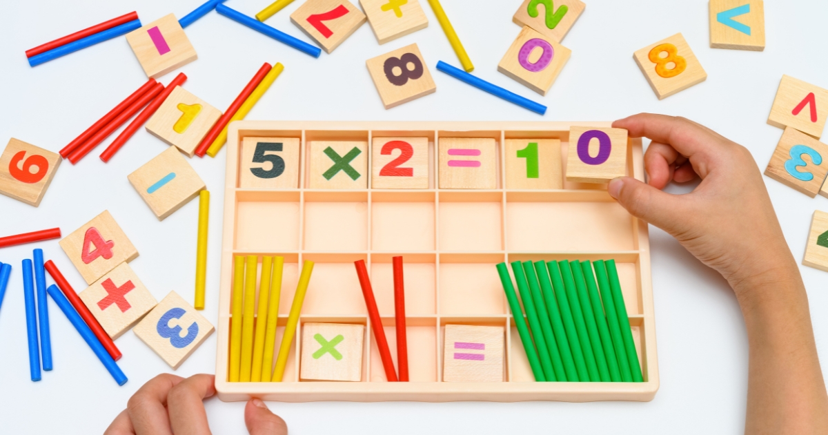 Hands-on multiplication learning activity using wooden number tiles and colorful counting sticks for homeschooling math education.