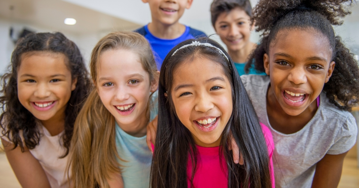 Group of happy and diverse children smiling together, representing socialization, confidence, and positive learning experiences in homeschooling.