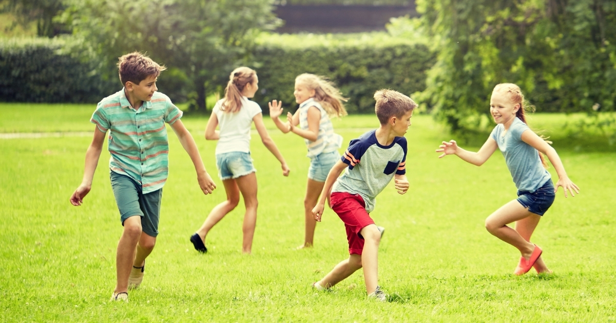 Kids running and playing tag outdoors, promoting active homeschool physical education.