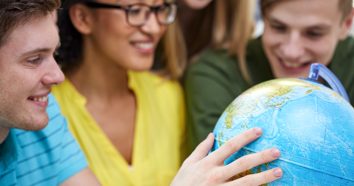 High school homeschool students studying geography with a globe, engaged in a hands-on learning activity.