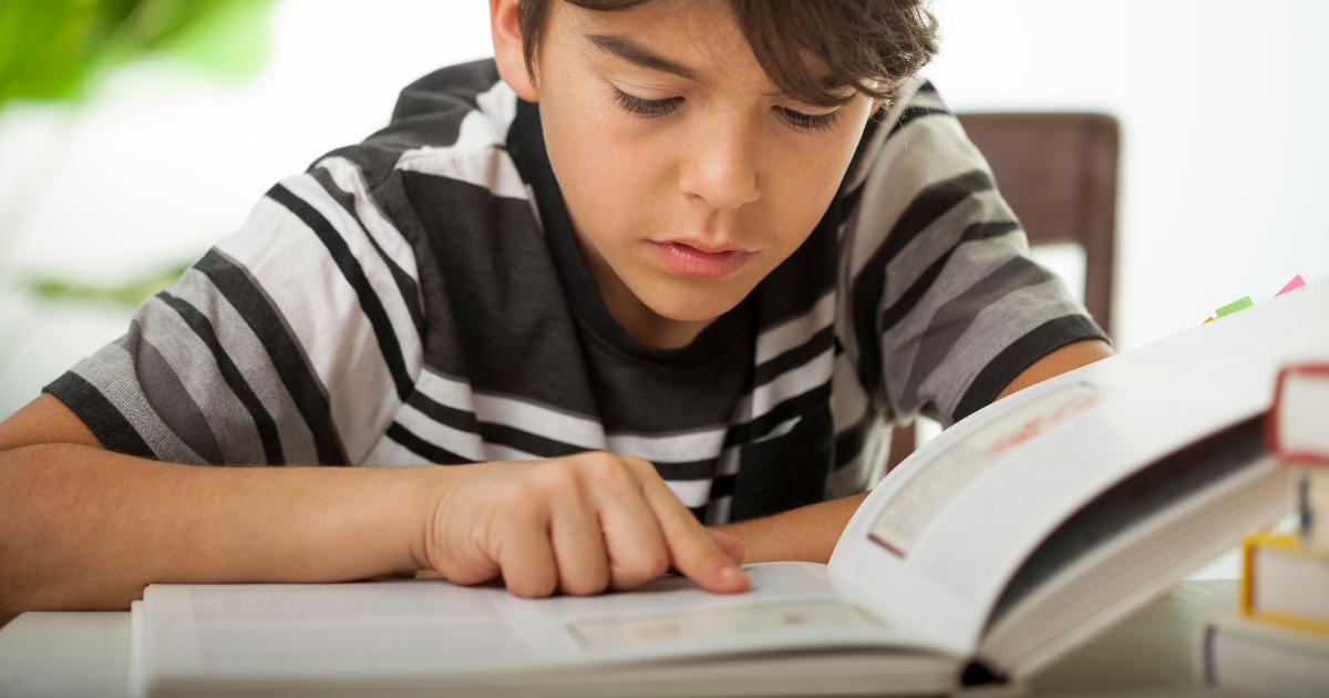 Focused homeschool student reading a textbook and studying, engaging in unplugged learning activities.