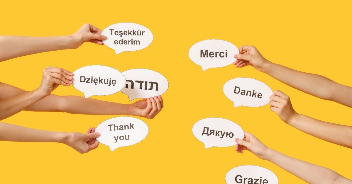 Multiple hands holding speech bubbles with 'Thank you' written in different languages, including English, French, German, Hebrew, Turkish, Polish, Ukrainian, and Italian, against a yellow background. A representation of multilingual learning and language diversity.